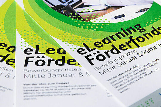 Foto von Broschüren zum e-Learning Förderfonds. die aufgefächert auf einer Oberfläche liegen.